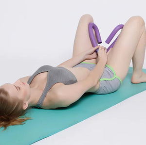 Woman exercising on a green mat with a purple portable thigh resistance trainer.