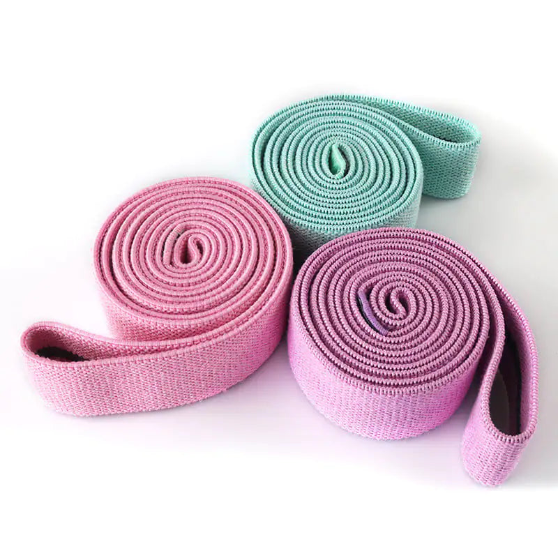 Three rolled-up full-length resistance bands (purple, pink and green) on a white background.