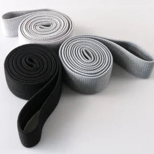 Three rolled-up full-length resistance bands (black,gray and white) on a white background.