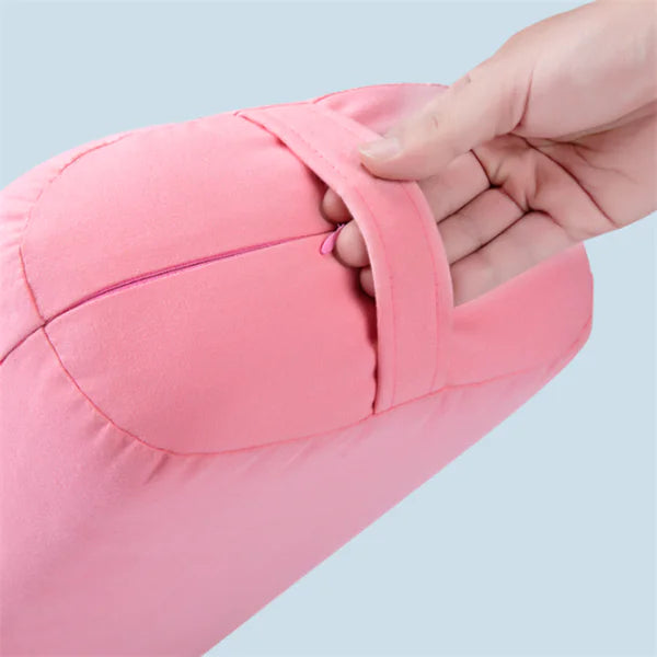Close-up of a hand holding a strap of a pink supportive yoga pillow against a light blue background.